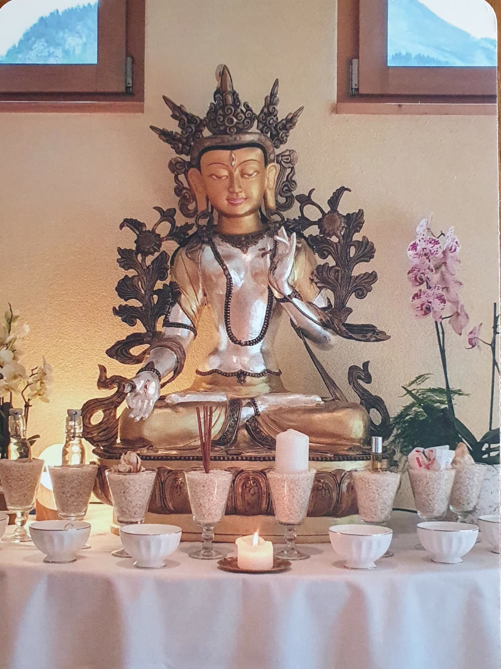 Vergoldete Tara-Statue mit Opfergaben und Orchideen im Karunahaus